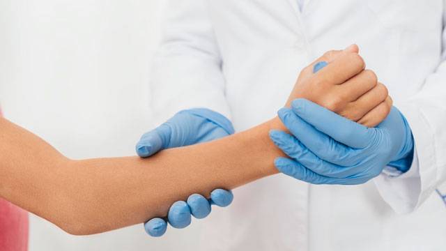 medico esamina la mano di una paziente che lamenta dolore